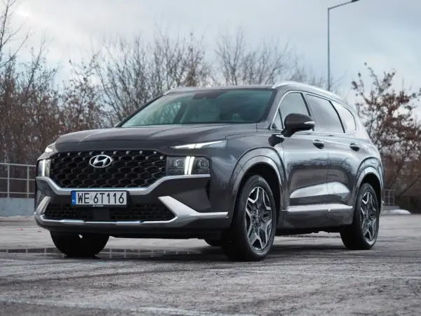 Ciemnoszary Hyundai Santa Fe z polskimi tablicami WE 6T116 stoi na parkingu.