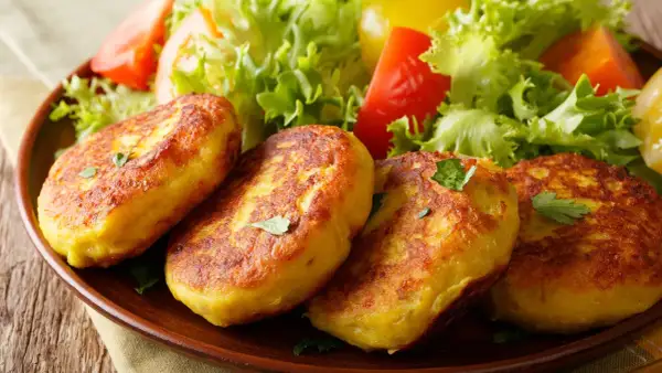 Goldbraune Kartoffelpuffer, nach Omas Kartoffelpuffer Rezept mit gekochten Kartoffeln, serviert mit frischem Salat.