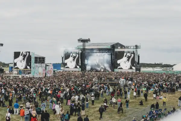Tłum ludzi na festiwalu, wielka scena z ekranami pokazującymi gitarę. To zapewne opener 2024 lineup.