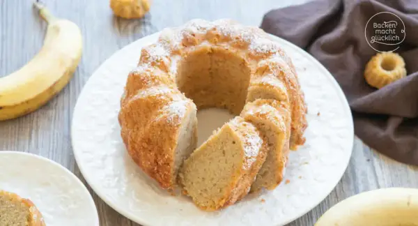 Reife Bananen verwerten: Ein saftiger Bananenkuchen mit Puderzucker bestäubt, daneben liegen frische Bananen.
