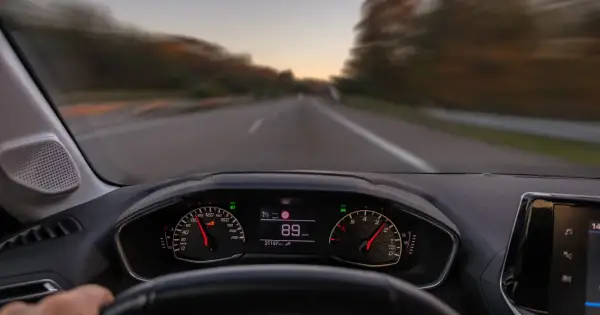 Widok z perspektywy kierowcy. Na desce rozdzielczej widać prędkościomierz wskazujący 89 km/h. To właśnie co robimy podczas jazdy samochodem.