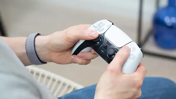 Hände halten einen weißen PS5-Controller, bereit für das PS4 auf PC streamen.
