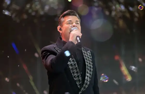Artysta w czarnym fraku z błyszczącymi zdobieniami śpiewa, a jego zielone oczy zdają się mówić: "akcent przez twe oczy zielone tekst".