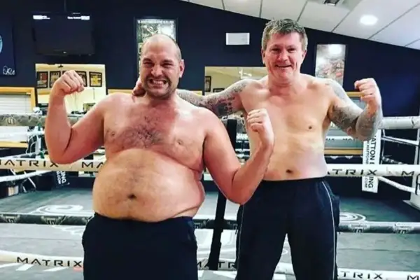 Tyson Fury's build is showcased as he poses shirtless with Ricky Hatton in a boxing ring, both flexing.