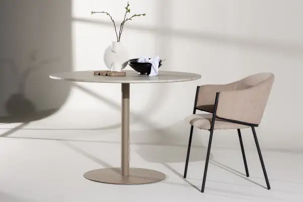 Runt matbord inspiration med en modern stol. En vas med kvistar och skålar på bordet.