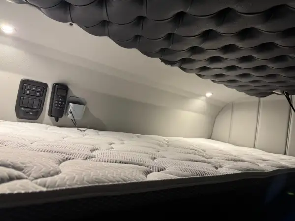 Confortable couchette camion americain avec matelas moelleux et commandes à portée de main.