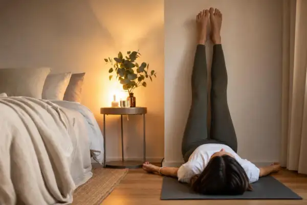 Donna in leggings esegue la posizione yoga con le gambe al muro, un esercizio che aiuta a sentirsi più leggeri e a dimagrire.