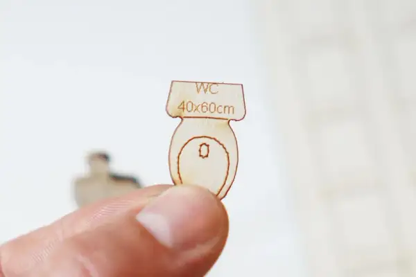 Miniature en bois d'une cuvette de WC, indiquant "WC 40x60cm", une suggestion pour la largeur minimum wc.