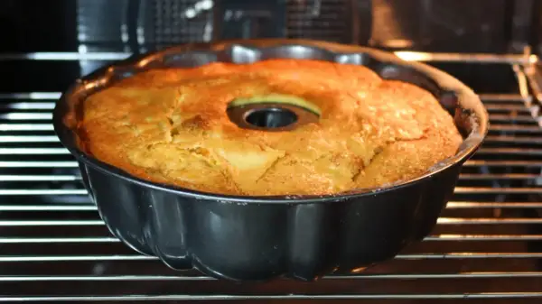 Bizcocho de manzana y naranja recién horneado en su molde, con un dorado perfecto. ¡Huele delicioso!