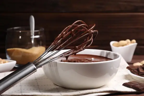 Frusta ricoperta di golosa crema pasticcera al cioccolato, pronta per essere gustata.