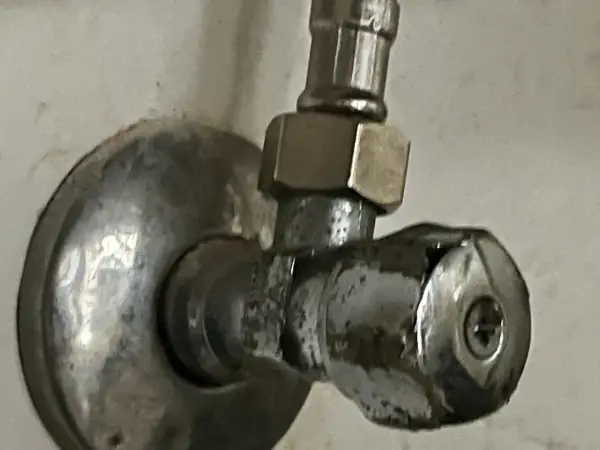 Metalowy zawór wody z uchwytem i śrubą.
