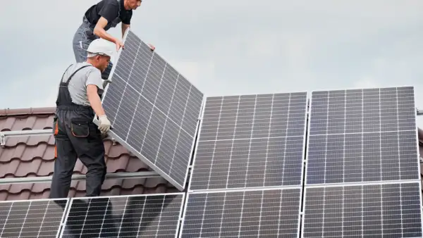 Instaladores colocan placas solares en un tejado, asegurando el anclaje para la energía limpia.