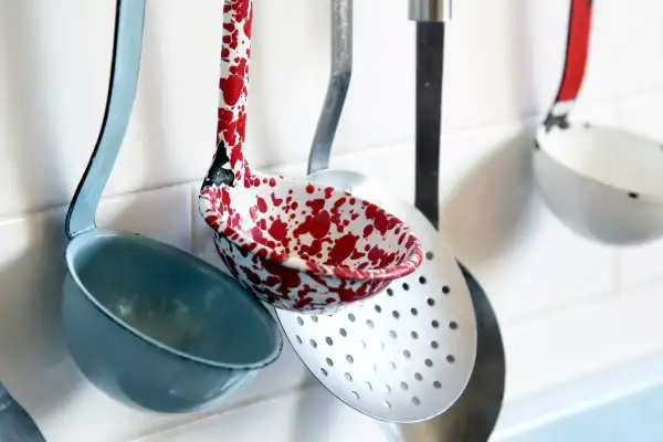 Utensili da cucina nomi: mestoli colorati e forati appesi al muro, pronti per preparare gustose ricette.
