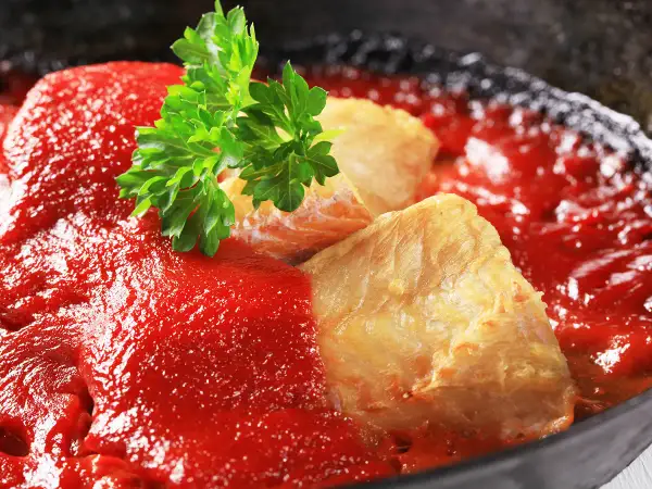 Délicieuse lotte recette en sauce tomate, garnie de persil frais. Un plat savoureux prêt à être dégusté.