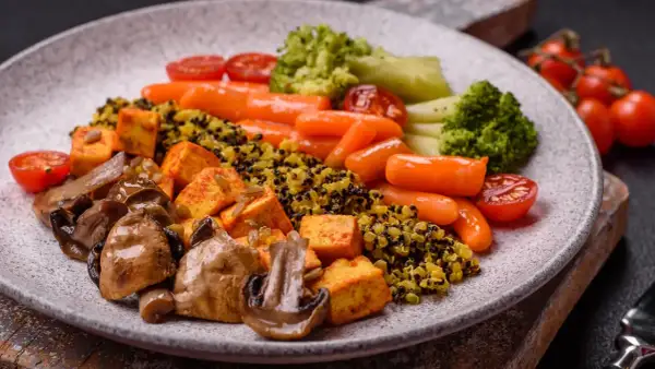 Gesundes Abendessen zum Abnehmen: Quinoa mit Tofu, Pilzen, Karotten, Brokkoli und Tomaten.