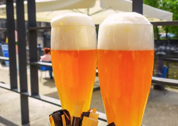Due bicchieri di hefeweizen birra dorata con schiuma bianca e soffice, pronti per essere gustati all'aperto.