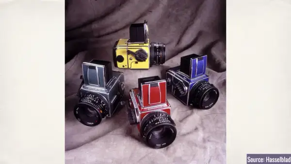 A collection of vintage Hasselblad 500c cameras in various colors: yellow, green, red, and blue.