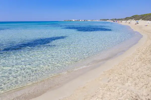 Spiaggia di Punta Prosciutto, Maldive del Salento. Acque cristalline e sabbia dorata sotto un cielo azzurro.