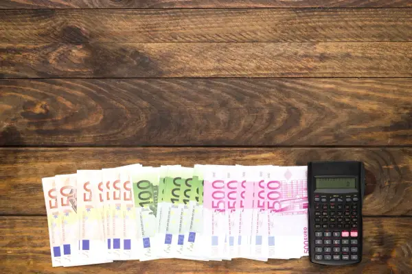 Banknoty euro i kalkulator na drewnianym tle.