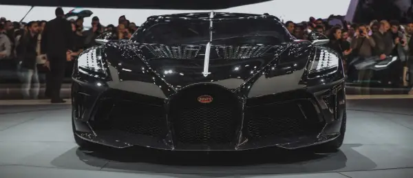 Czarny Bugatti, najdroższe auto na świecie, błyszczy na wystawie, przyciągając wzrok tłumu.