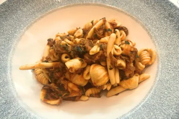 Un piatto invitante di trofie alla carlofortina, con pasta fresca e un ricco sugo di pesce.