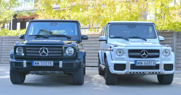 Dwa luksusowe Mercedesy klasy G, czyli gelendy, stoją obok siebie. Jedna jest ciemnozielona, druga biała.