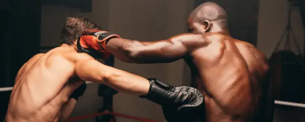 Two boxers in a ring, one landing a powerful cross combination punch. Sweat glistens on their muscular bodies.