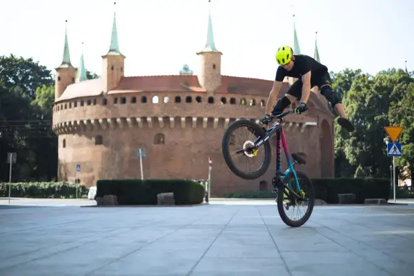 Kaskader na rowerze wykonuje trik przed Barbakanem w Krakowie. To niesamowity pokaz velo kraków!