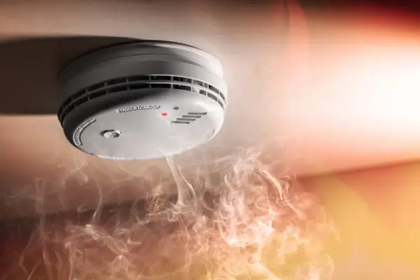 Détecteur de fumée au plafond, avec une petite lumière rouge allumée. Comment savoir si mon détecteur de fumée fonctionne ? La fumée tourbillonne en dessous.