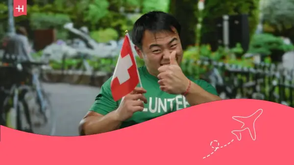 Hombre con bandera suiza y camiseta de voluntario, pulgar arriba. ¡Orgulloso de su voluntariado suizo!