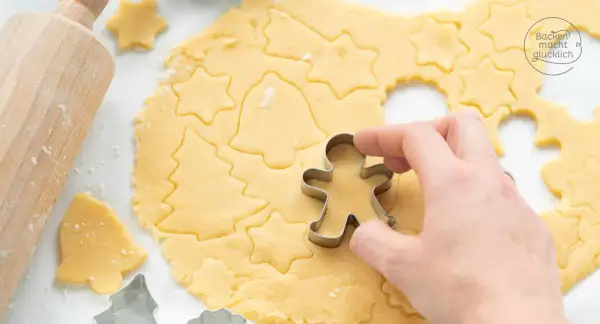 Mit diesem Kekse Rezept entstehen Sterne, Tannenbäume und Lebkuchenmännchen. Ein Holz-Nudelholz liegt daneben.