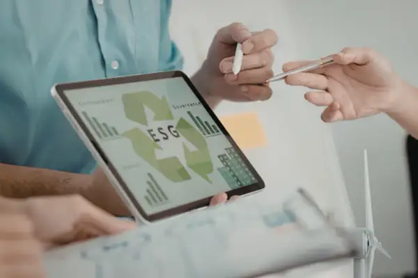 Zespół analizuje dane ESG na tablecie, planując strategię zrównoważonego rozwoju. To kluczowy element nowoczesnego system zarządzania energią ems.