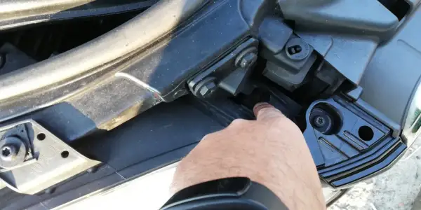 Palec wskazuje śrubę mocującą reflektor podczas wymiany żarówki audi a4 b7 przód prawa.