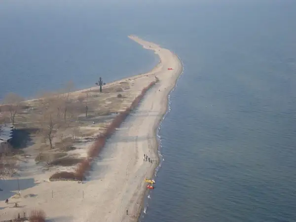 Półwysep w Rewie z krzyżem i plażą. Atrakcje turystyczne tego miejsca przyciągają spacerowiczów.
