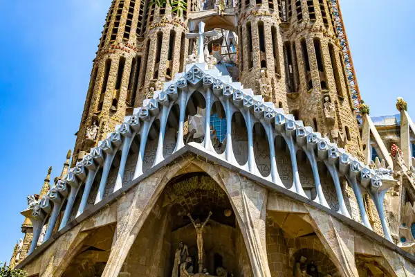 Intricate Gaudi art adorns the Sagrada Familia, with stone carvings and arched facades reaching towards a bright blue sky.