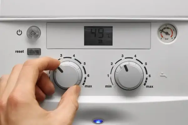 Mano che regola la caldaia spenta gas aperto. Il display mostra 49°C.