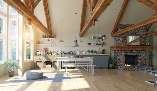 Jasna kuchnia w stylu modern farmhouse z kamiennym kominkiem, drewnianymi belkami i dużymi oknami.