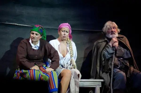 Chłopi na scenie Teatru Muzycznego Gdynia, w strojach ludowych, z wyrazem smutku na twarzach.