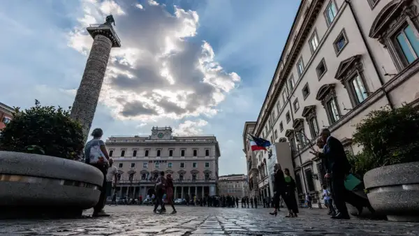 La Colonna di Marco Aurelio domina la piazza, con edifici storici e persone che passeggiano a Piazza Colonna, Roma.