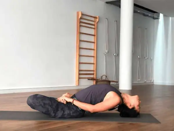 Mujer en postura de yoga Matsyasana, disfrutando de la apertura de pecho yoga beneficios.