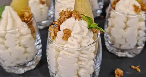 Ljuvlig vispad pannacotta i glas, toppad med krispiga nötter och en bit päron. En perfekt dessert!