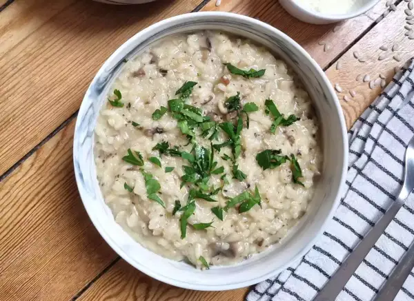 Kremowe risotto z grzybami, przygotowane w Thermomixie, posypane świeżą natką pietruszki. Idealne danie na obiad.