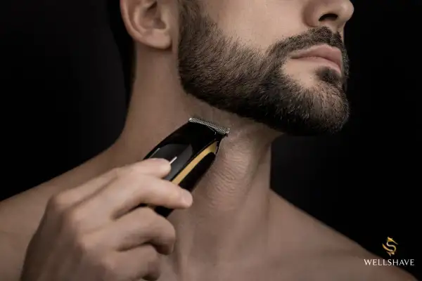 Un homme utilise une tondeuse pour sculpter sa barbe, visant une barbe parfaite.