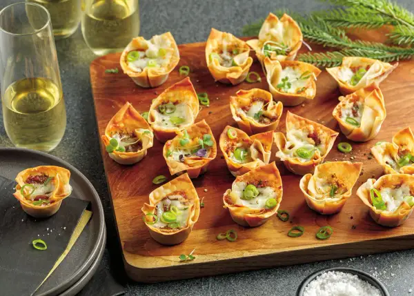 Petits feuilletés croustillants garnis d'effiloché de canard en feuille de brick, parsemés de ciboule et de fromage fondu.