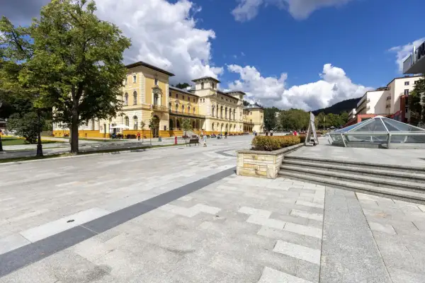 Piękny, słoneczny dzień w uzdrowisku. Ludzie spacerują po placu przed zabytkowym budynkiem. Zastanawiasz się, jak sprawdzić kolejkę do sanatorium?