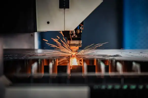 Precyzyjna obsługa maszyn CNC: laser tnie metal, sypią się iskry.