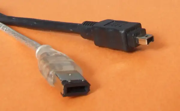 Dwa kable: jeden przezroczysty z szeroką wtyczką, drugi czarny z małą wtyczką. To złącza FireWire IEEE 1394.