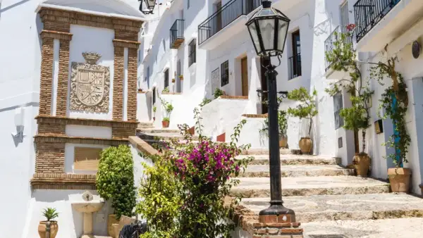 Escaleras empedradas y casas blancas adornadas con flores, un escudo de armas y una farola. Descubre qué ver en Frigiliana, un pueblo blanco andaluz.
