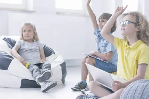 Niños participando en juegos en inglés para niños, levantando las manos con entusiasmo.