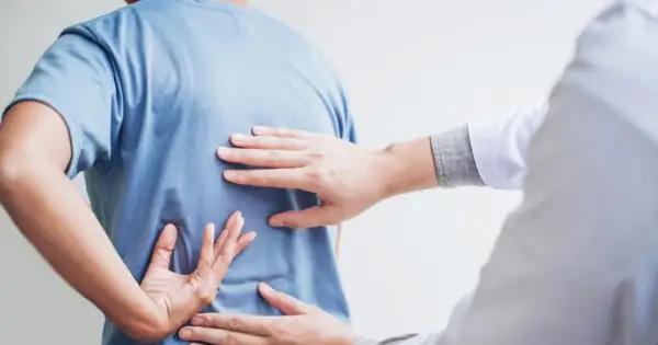 Dłoń terapeuty bada plecy pacjenta, szukając oznak bólu. Może to być wstęp do terapii, ale warto pamiętać o potencjalnych skutkach ubocznych nastawiania kręgosłupa.